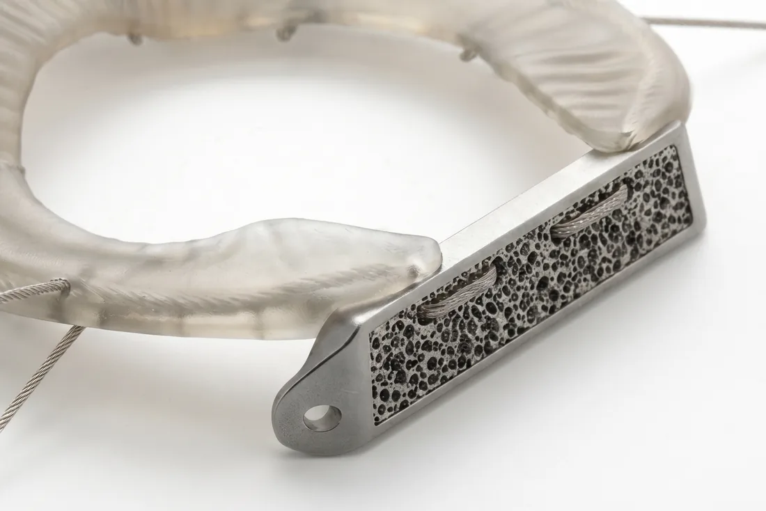 Close view of the LunaFlex fixation bridge, a metal plate with a porous surface structure, joined to the translucent composite body of the implant.